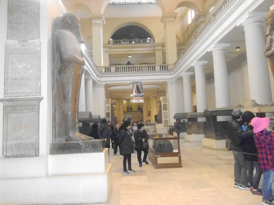 Ēģiptes muzeja zāle ar senām statujām un apmeklētājiem